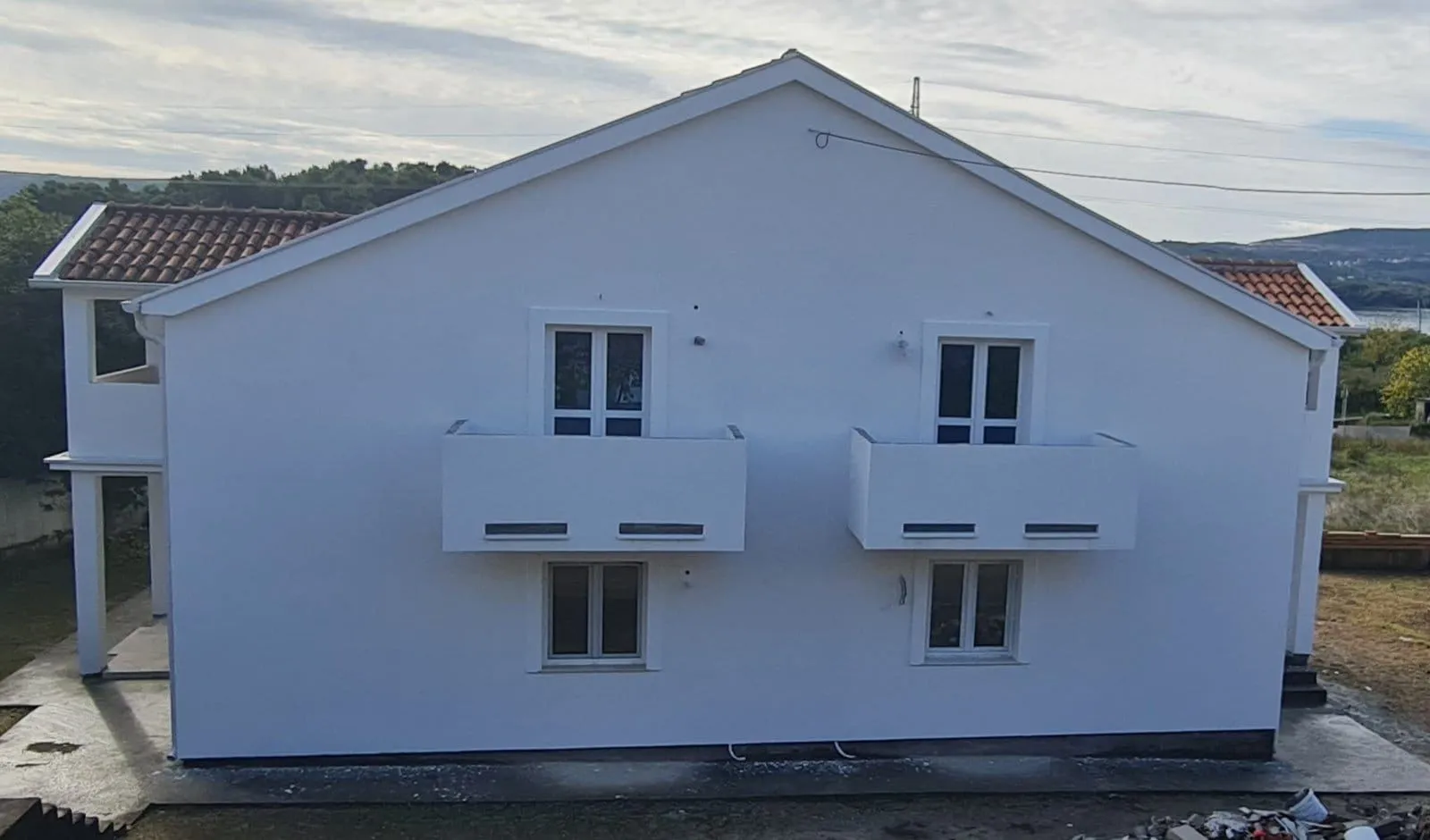 Prednja strana bijele kuće sa balkonima i prozorima.