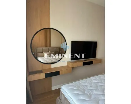Bedroom with a double bed, large round mirror, and wall-mounted television. - image 11