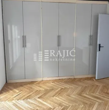 Bedroom with a large built-in wardrobe and parquet flooring. - image 11