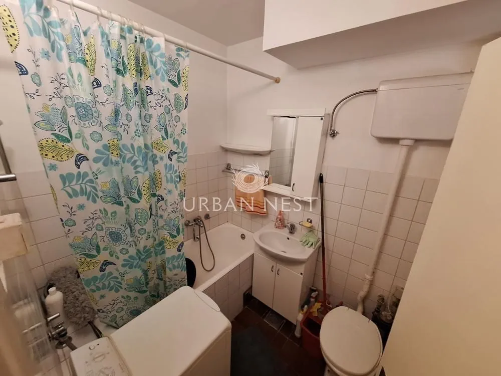 Smaller bathroom with a bathtub, washbasin, toilet, and washing machine.