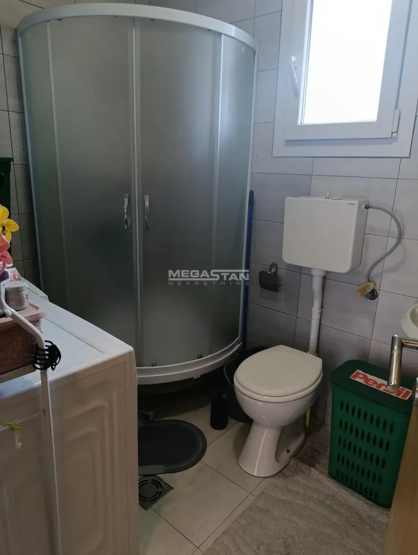 Small bathroom with a shower cabin, toilet, and washing machine.