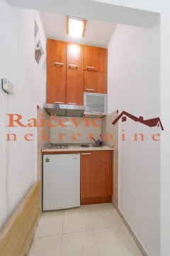 Mala kuhinja sa drvenim elementima, frižiderom i ugradnom pločom. - image 9