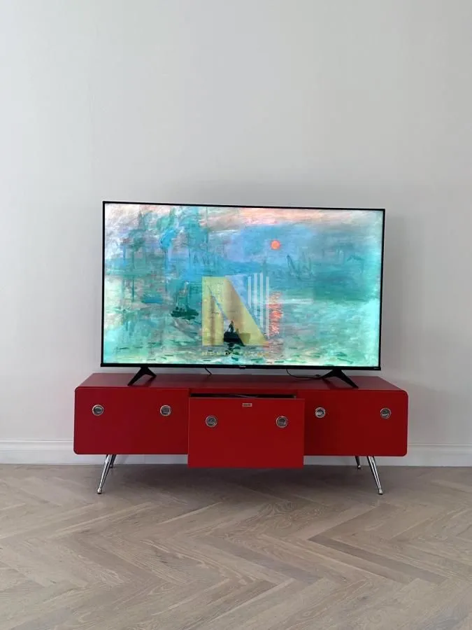 Televizor na crvenoj komodi u dnevnoj sobi.