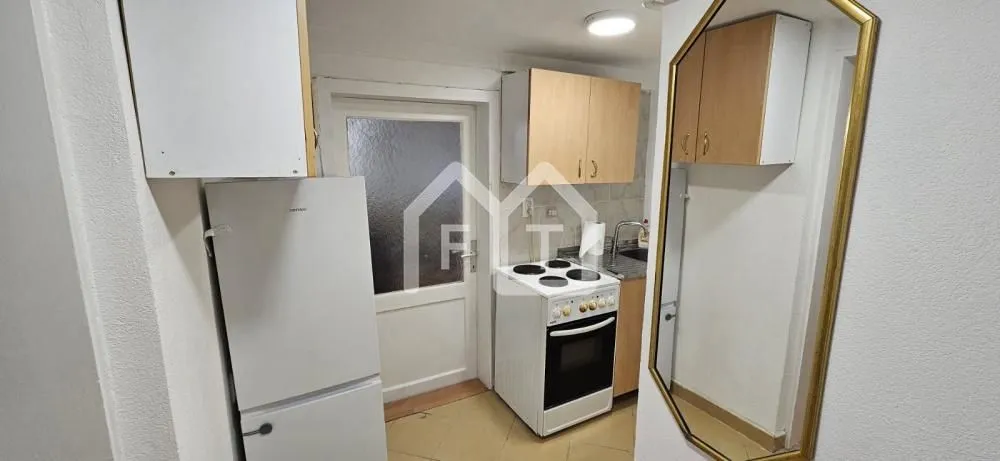 Small kitchen with a stove, refrigerator, and wooden cabinetry.