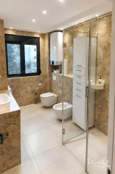 Modern bathroom with a shower enclosure, toilet, bidet, and a window. - image 11