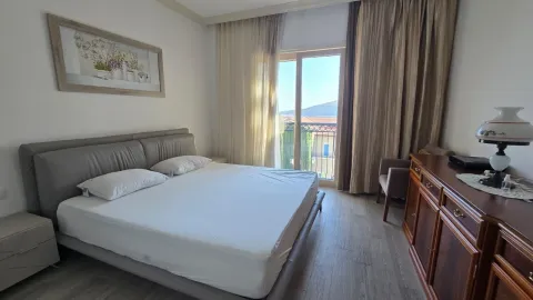 Spavaća soba sa bračnim krevetom, drvenom komodom i izlazom na balkon. - image 6