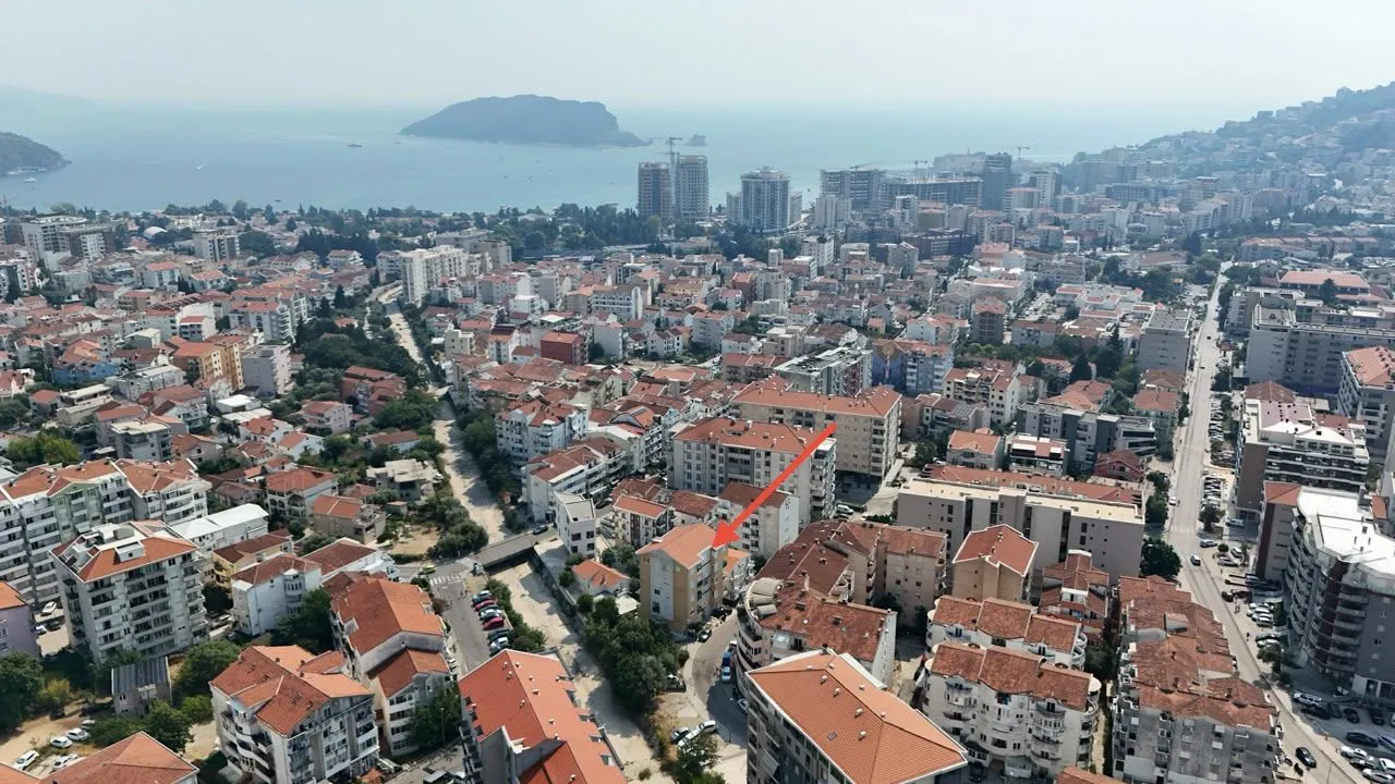 Pogled iz vazduha na grad i zgradu označenu crvenom strelicom.
