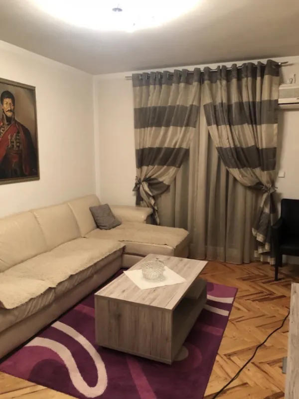 Dnevna soba sa ugaonom garniturom, klub stočićem i slikom na zidu.