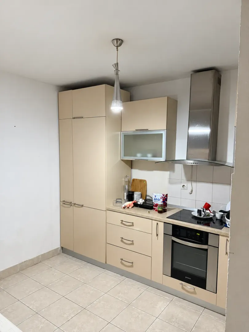 Compact kitchen with beige cabinetry, built-in oven, and extractor hood.