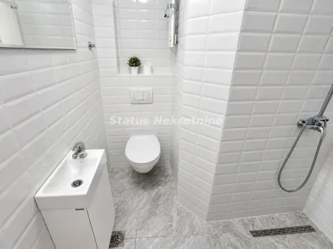 Manje kupatilo obloženo belim keramičkim pločicama sa tuš kabinom. - image 2
