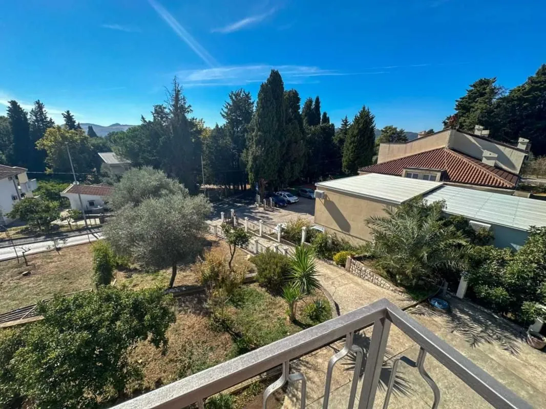 Pogled sa balkona na dvorište, okolne kuće i zelenilo.