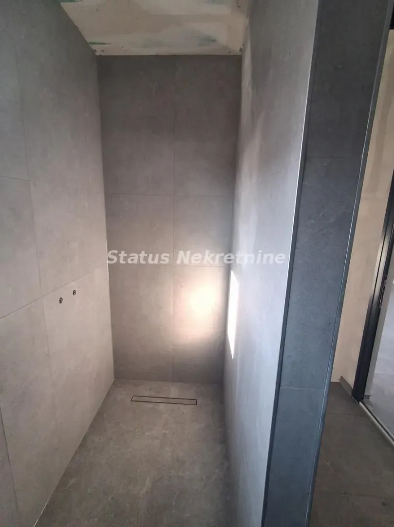 View of an unfinished bathroom lined with gray tiles with a built-in drain.