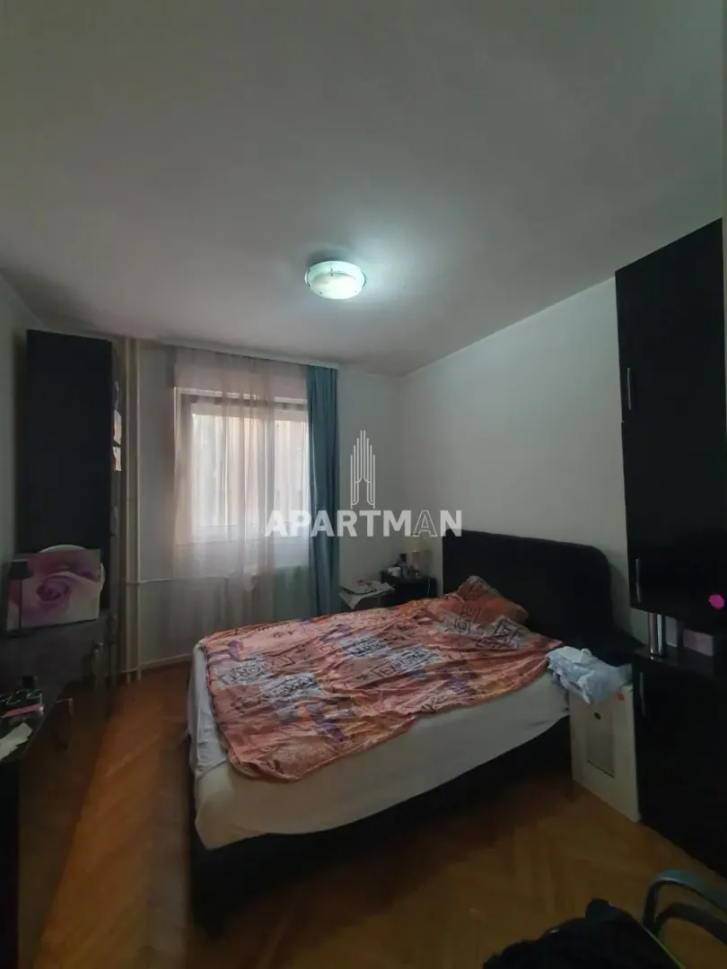 Nameštena spavaća soba sa bračnim krevetom, ormarima i prozorom.