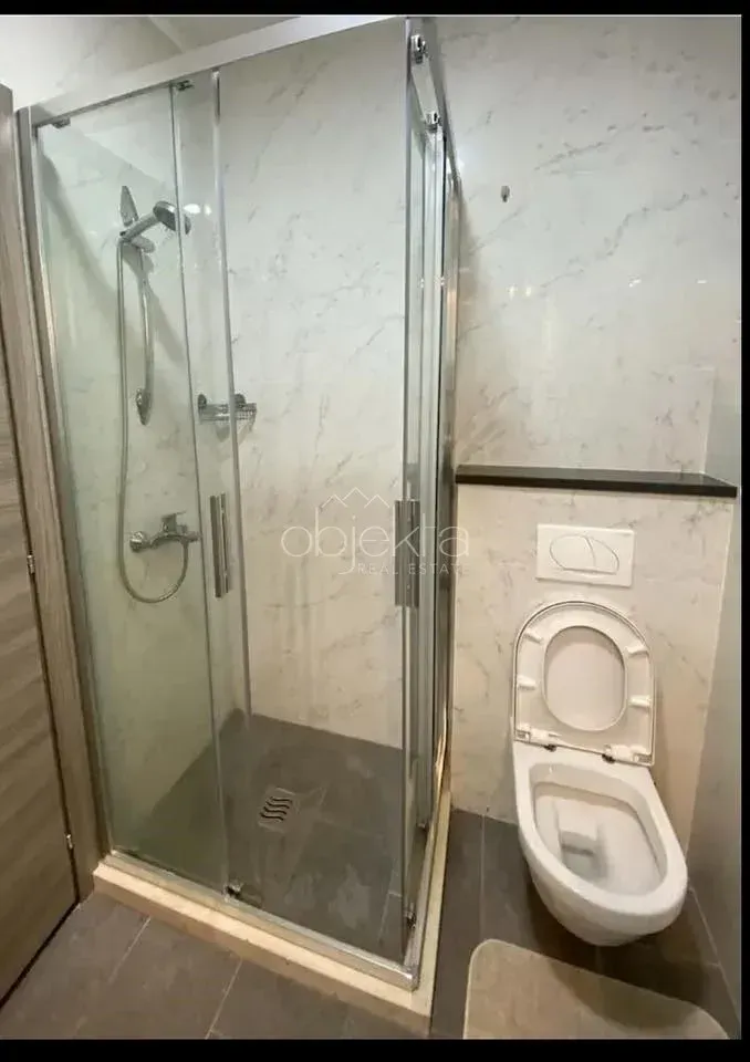 Bathroom with a shower enclosure and a wall-mounted toilet.