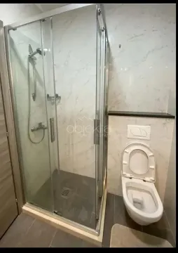 Bathroom with a shower enclosure and a wall-mounted toilet. - image 10