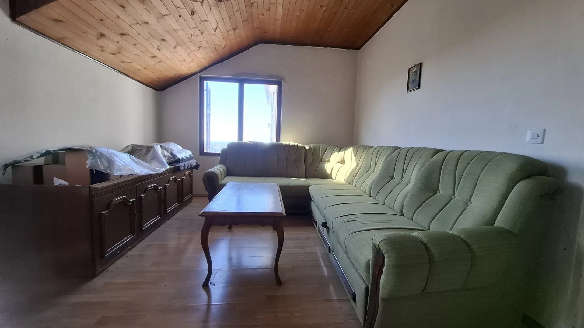 Dnevna soba sa garniturom i drvenim plafonom.
