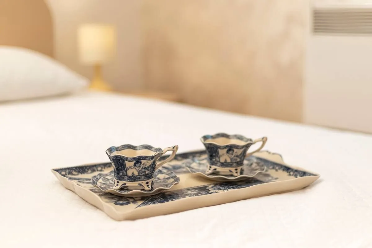 Decorative coffee cups with saucers on a bed in the bedroom.