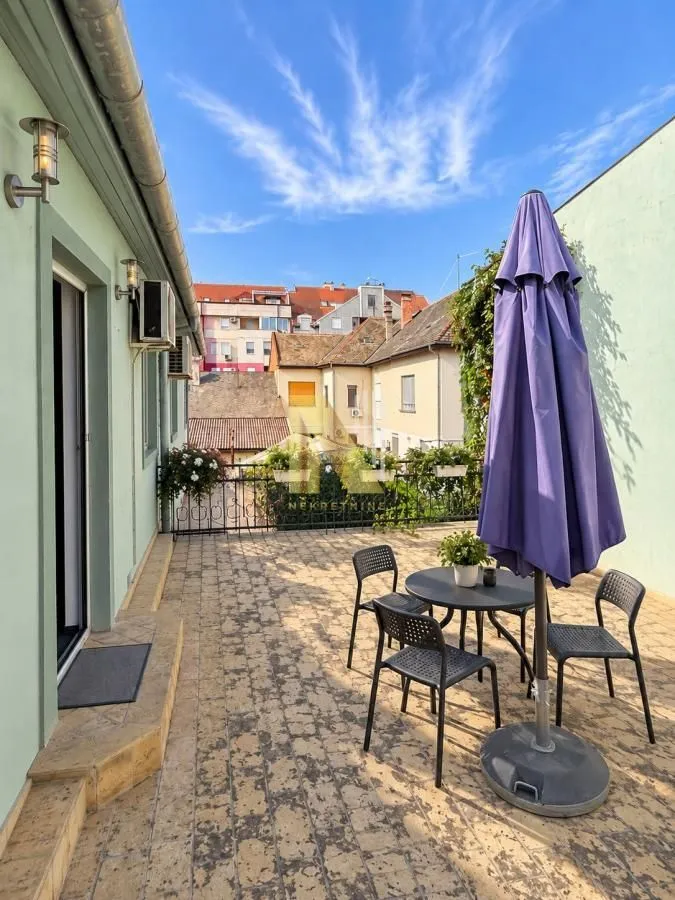 Spacious terrace with patio furniture and an umbrella.