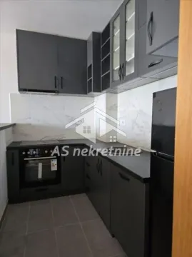 Modern kitchen with dark cabinetry and white marble-look tiles. - image 2