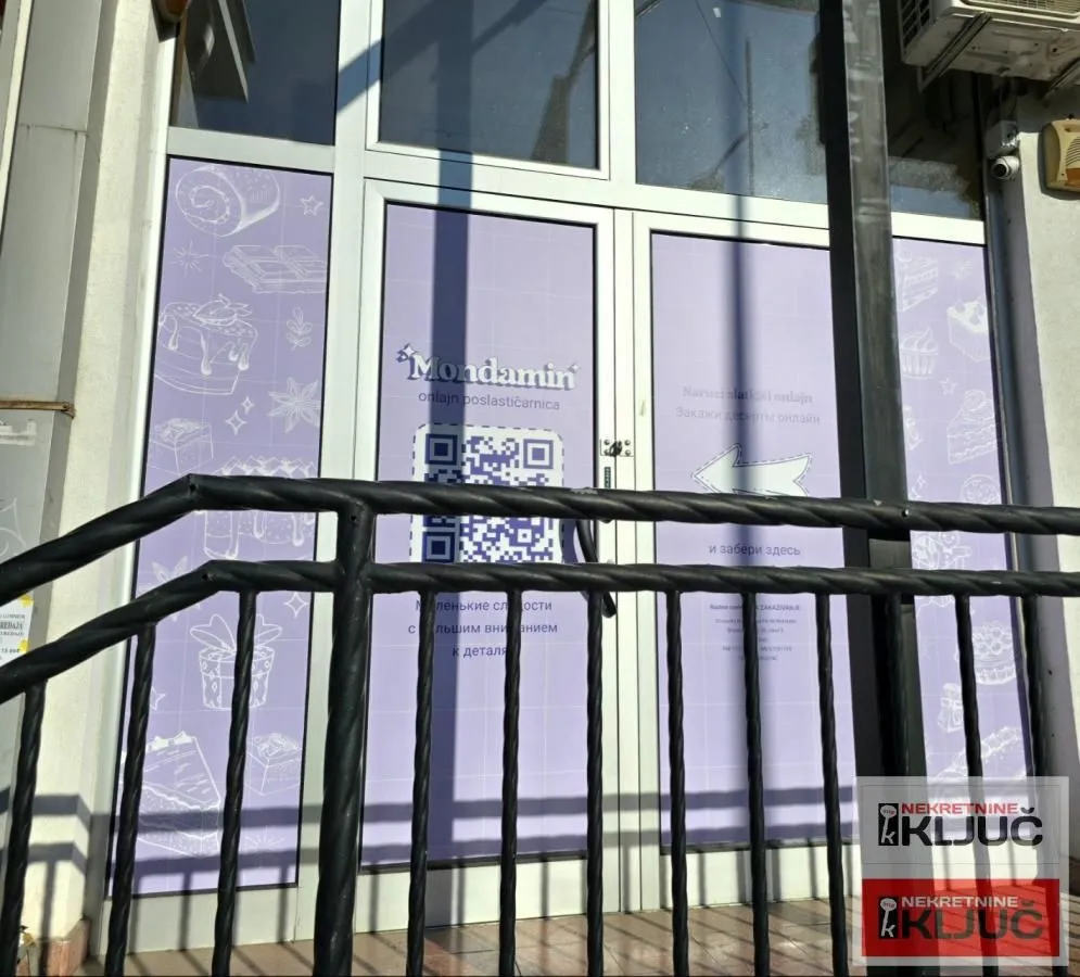 Entrance to a commercial space with a glass storefront and a metal railing.