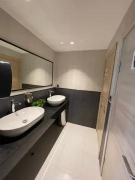 Modern bathroom with two countertop sinks, a large mirror, and dark tiles. - image 34