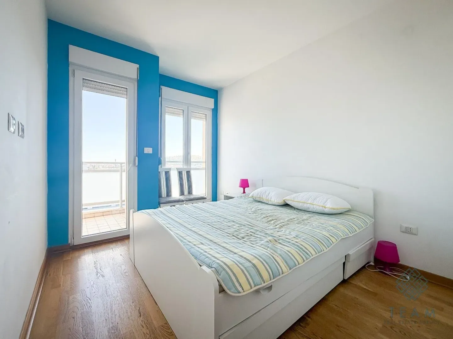 Bedroom with a double bed, a blue accent wall, and access to the balcony.