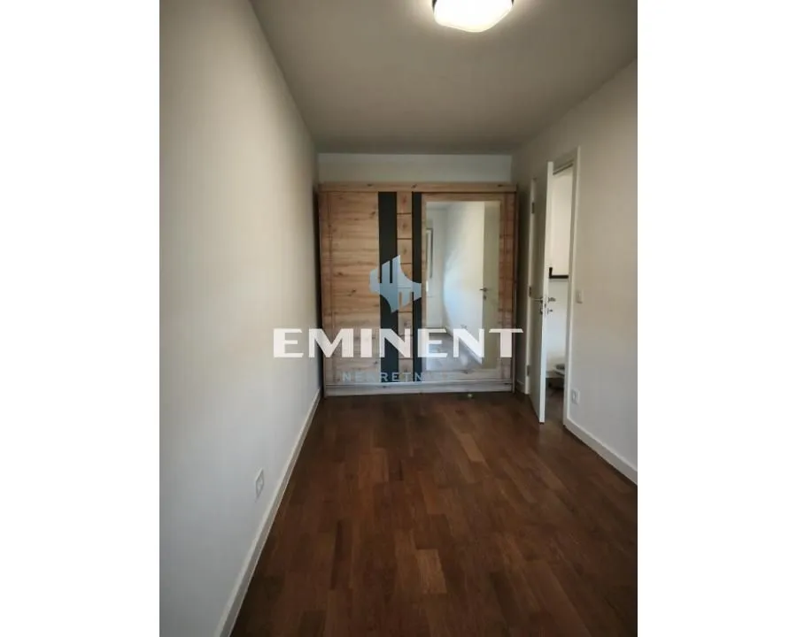 Small bedroom with a wooden wardrobe and laminate flooring.