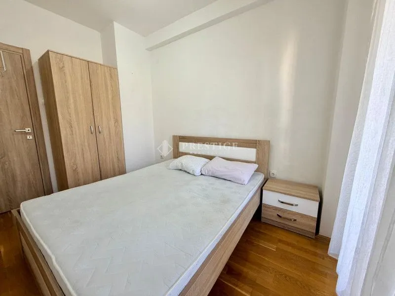 Namještena spavaća soba sa bračnim krevetom, plakarom i noćnim stočićem.