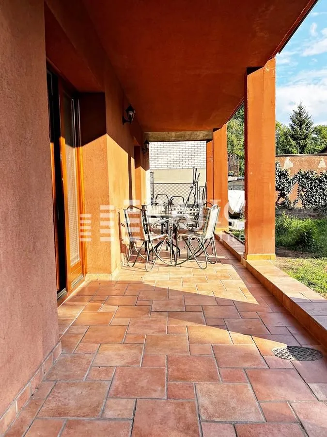 Covered terrace with ceramic tiles and patio furniture.