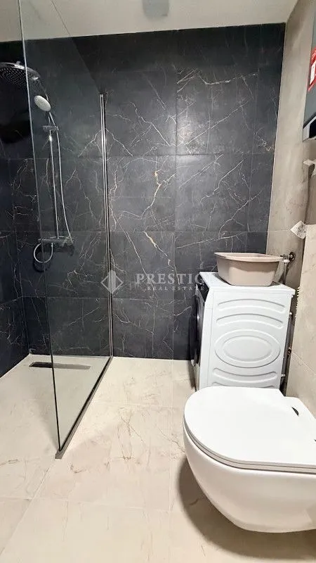 Moderno opremljeno kupatilo sa tuš kabinom i veš mašinom.