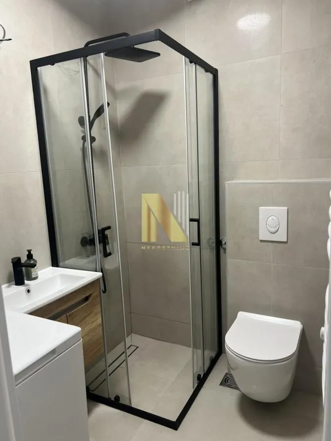Modern bathroom with a shower cabin, washbasin, and toilet.