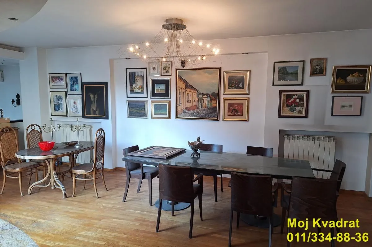 Dnevna soba sa trpezarijskim stolom i umetničkim slikama na zidu.