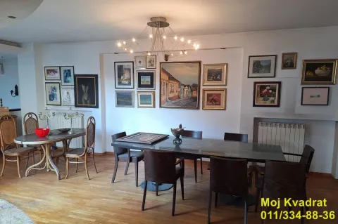 Dnevna soba sa trpezarijskim stolom i umetničkim slikama na zidu. - image 2
