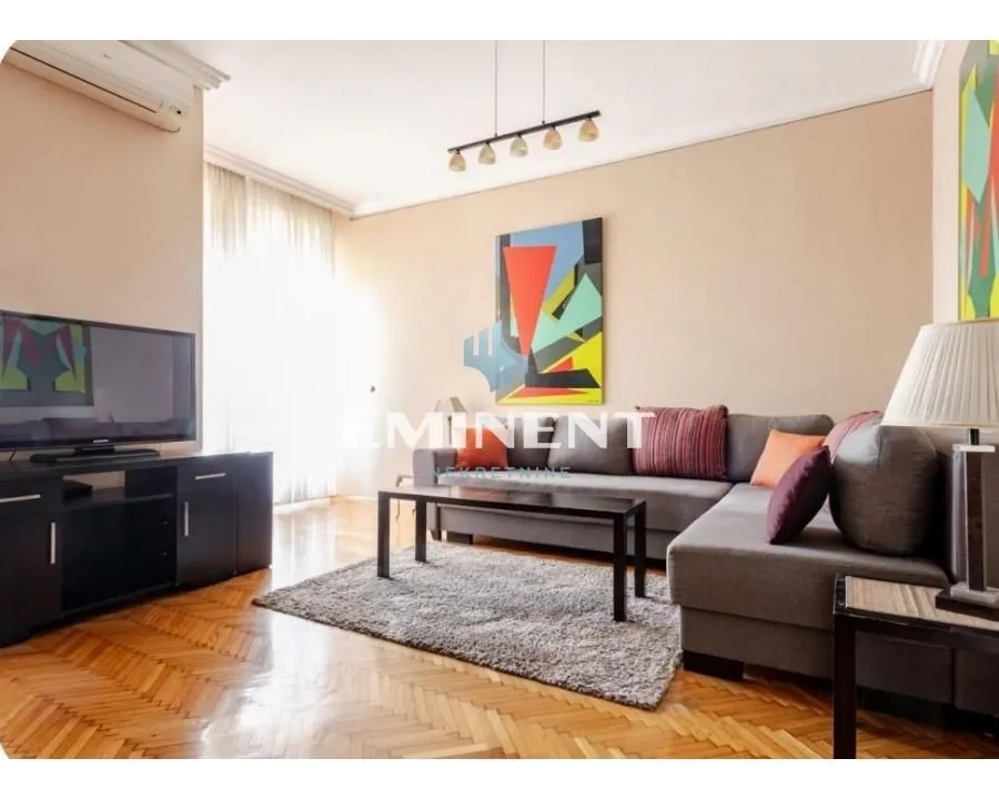 Living room with a sectional sofa, TV, and parquet flooring.