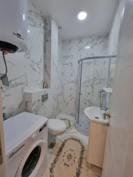 A bright bathroom with a shower cabin and a washing machine. - image 8