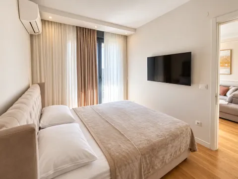 Udobna spavaća soba sa bračnim krevetom, klima-uređajem i televizorom na zidu. - image 5