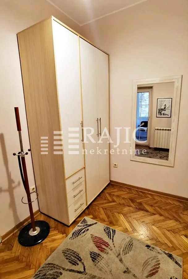 Bedroom with a large wardrobe, parquet flooring, and a wall mirror.
