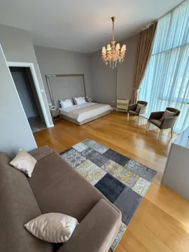 Spacious bedroom with a double bed, seating area, and large windows. - image 7