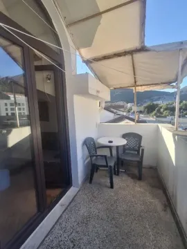Natkrivena terasa sa stolom i stolicama i pogledom na okolinu. - image 2
