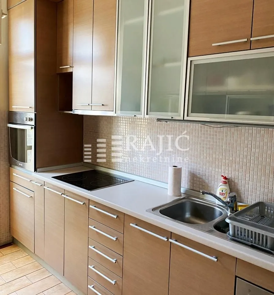 Modern kitchen with wooden cabinetry and built-in appliances.