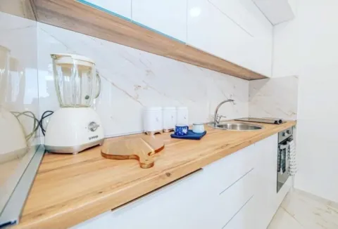 View of the kitchen counter with a sink, built-in oven, and kitchen appliances. - image 3