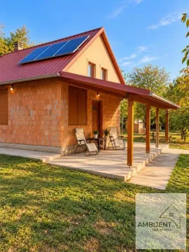 Pogled na spoljašnjost kuće sa natkrivenom terasom, dvorištem i solarnim panelima na krovu. - image 16