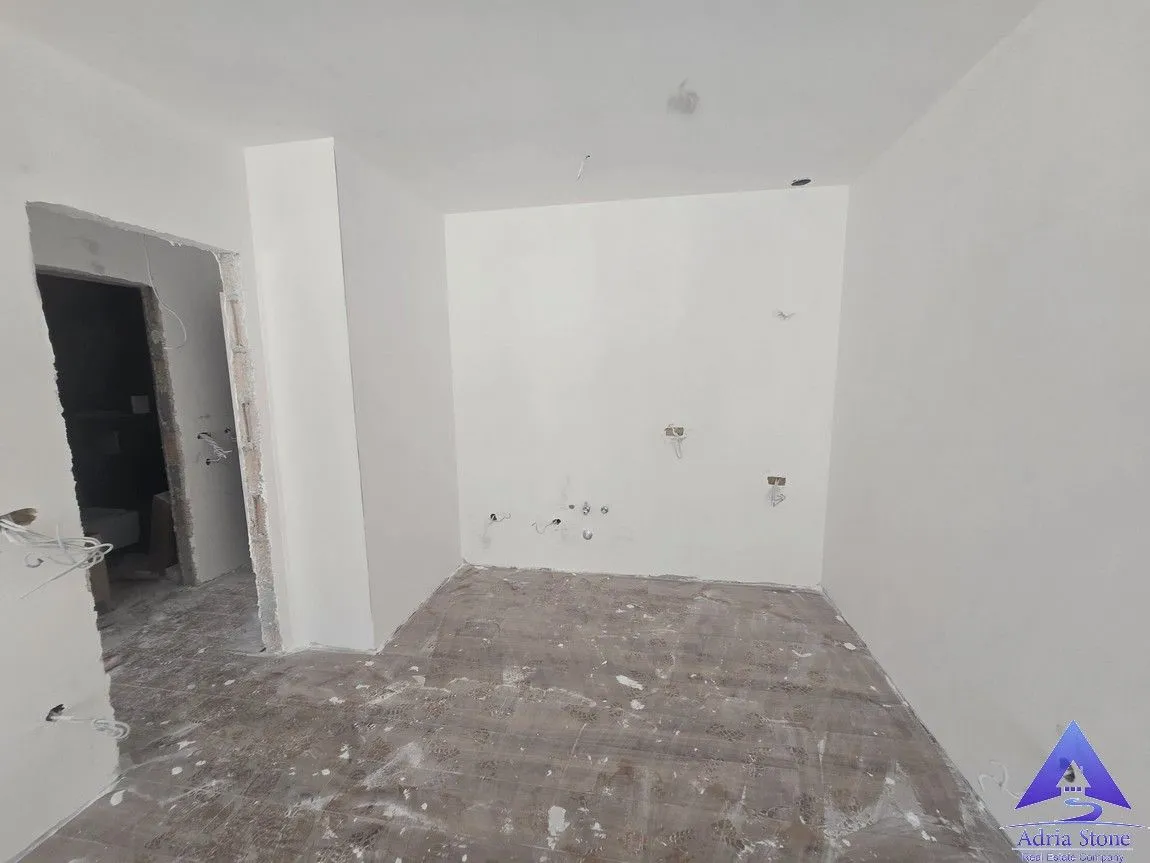 Pogled na nenamještenu prostoriju u fazi renoviranja sa bijelim zidovima.