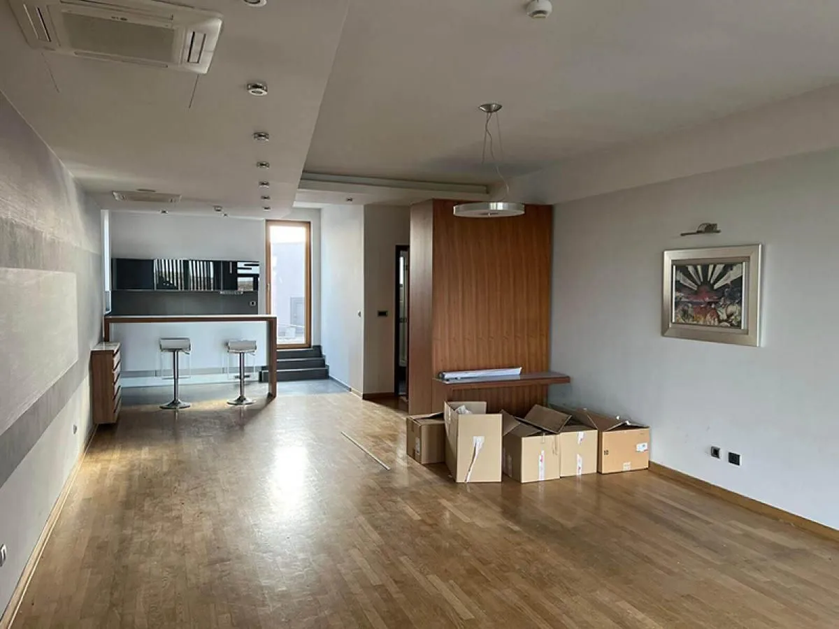 Spacious living room with wooden flooring and moving boxes.