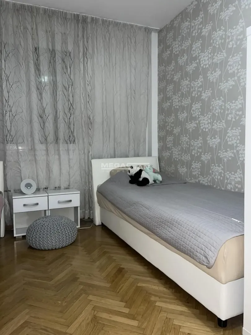 Bedroom with a bed, a bedside table, and wallpapered walls.