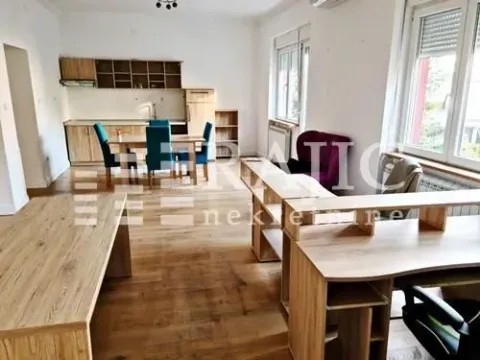 Spacious room with office desks and a kitchen in the background. - image 2