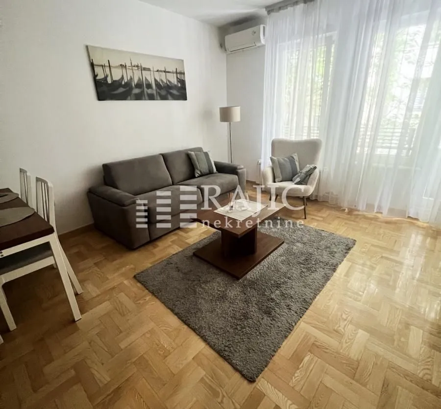 Living room with a sofa, armchair, and dining table.