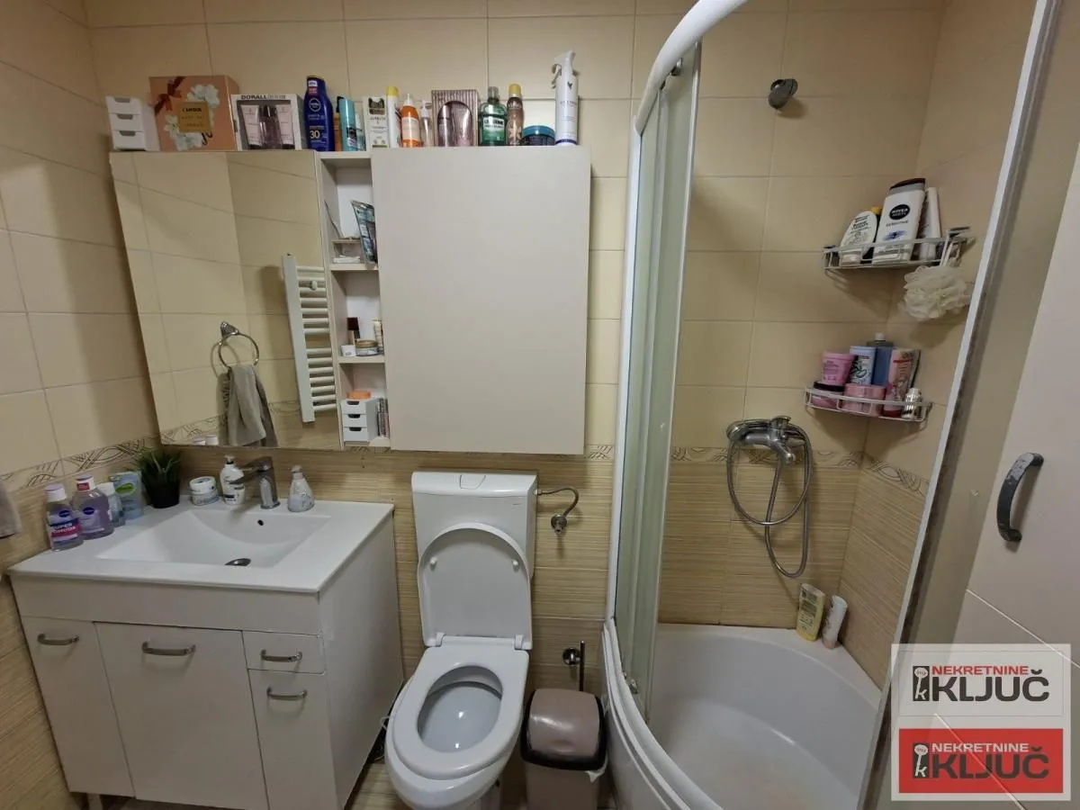 Kupatilo opremljeno umivaonikom, WC šoljom, tuš kabinom i zidnim ormarićem.