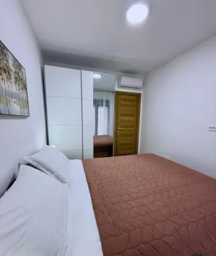 Furnished bedroom with a double bed, white wardrobe, and air conditioning unit. - image 5