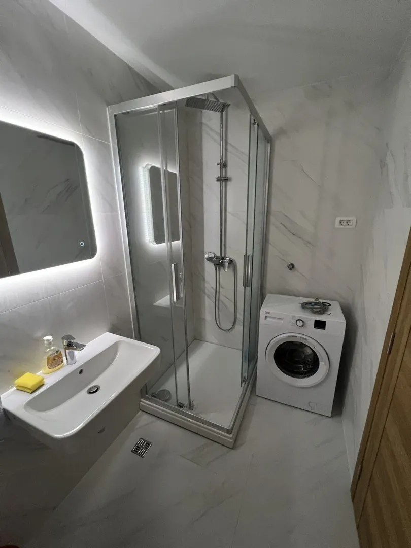 Modern bathroom with a shower cabin and washing machine.